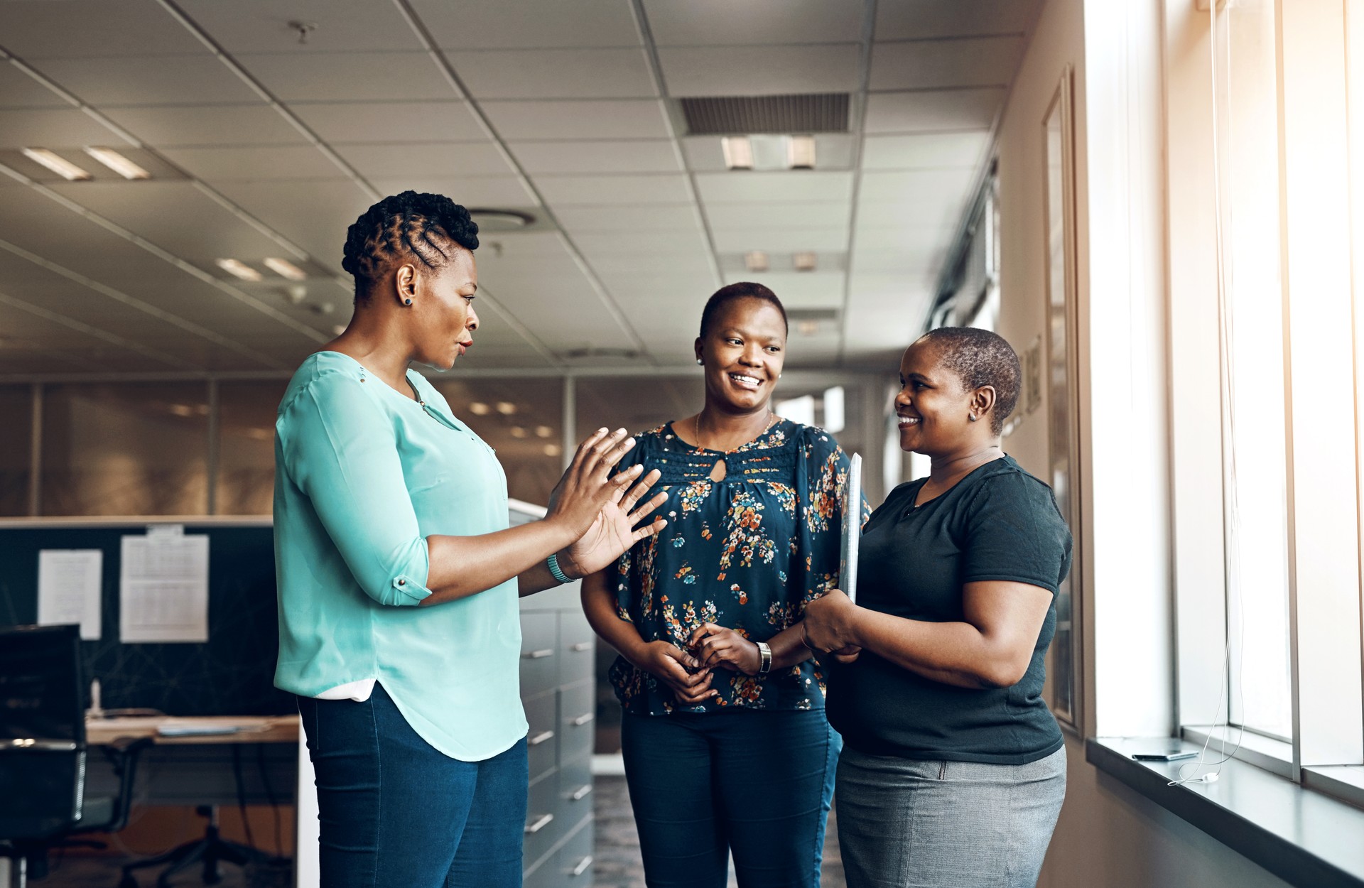 Office, chat and business people with smile in conversation for teamwork, planning and coaching. Happy, black women and employees with communication at work for administration, support and feedback