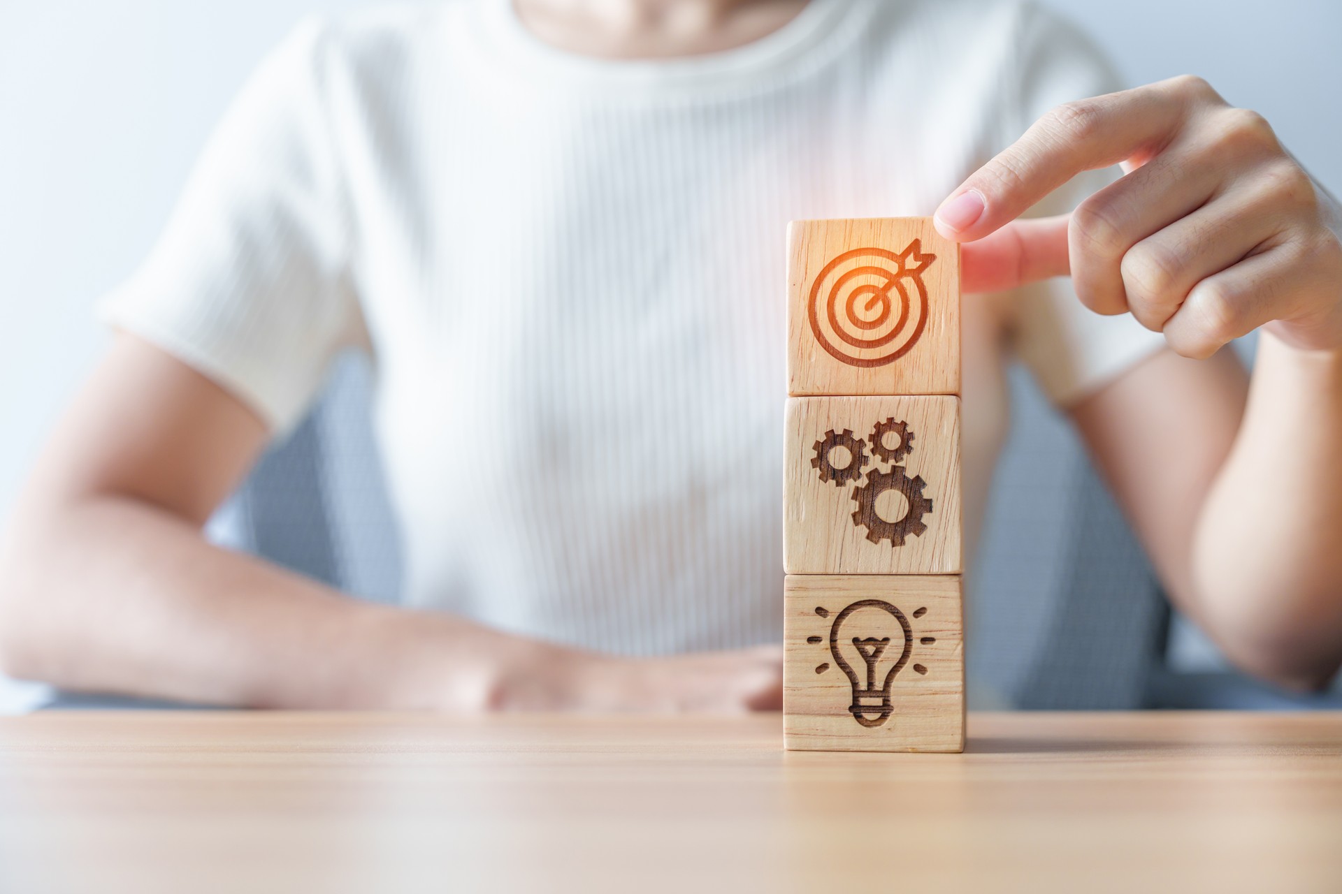 Woman hand holding dartboard above Gear and Lightbulb icon block. business planning process, goal, strategy, target, mission, action, objective, teamwork and idea concept